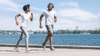 Young African American Man and Woman jogging near water
