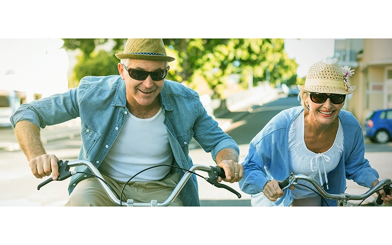 older couple riding bikes, enjoying Total Body Wellness